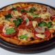 Pizza Capreze sa paradajzom, trapistom, kackavanjem sa dodacima povrca posluzeno na dasci